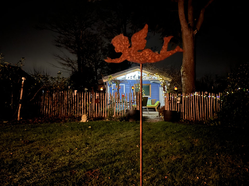 Staketenzaun beleuchtet mit Gartenhaus und Edelrostengel